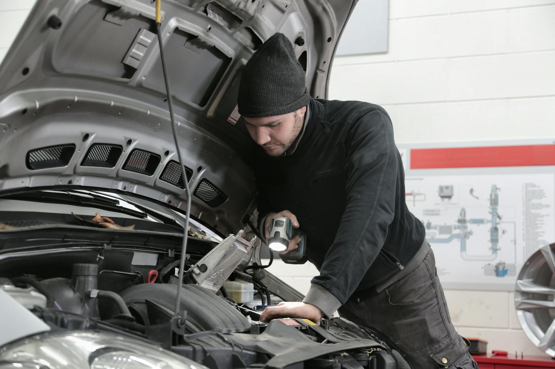 Mechanik z latarką dokładnie ogląda silnik używanego auta Kia