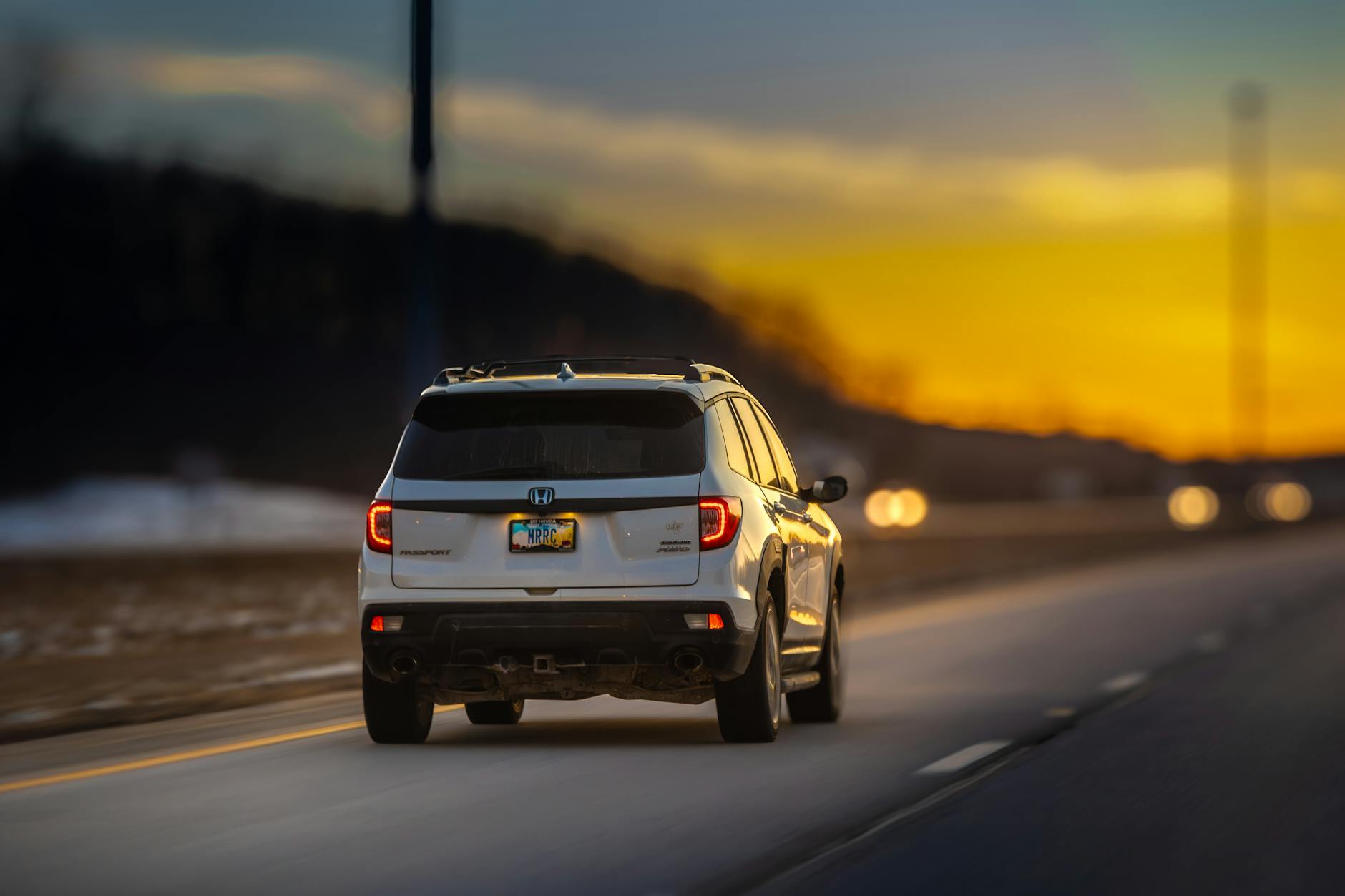 Białe SUV jedzie pustą autostradą o zachodzie słońca