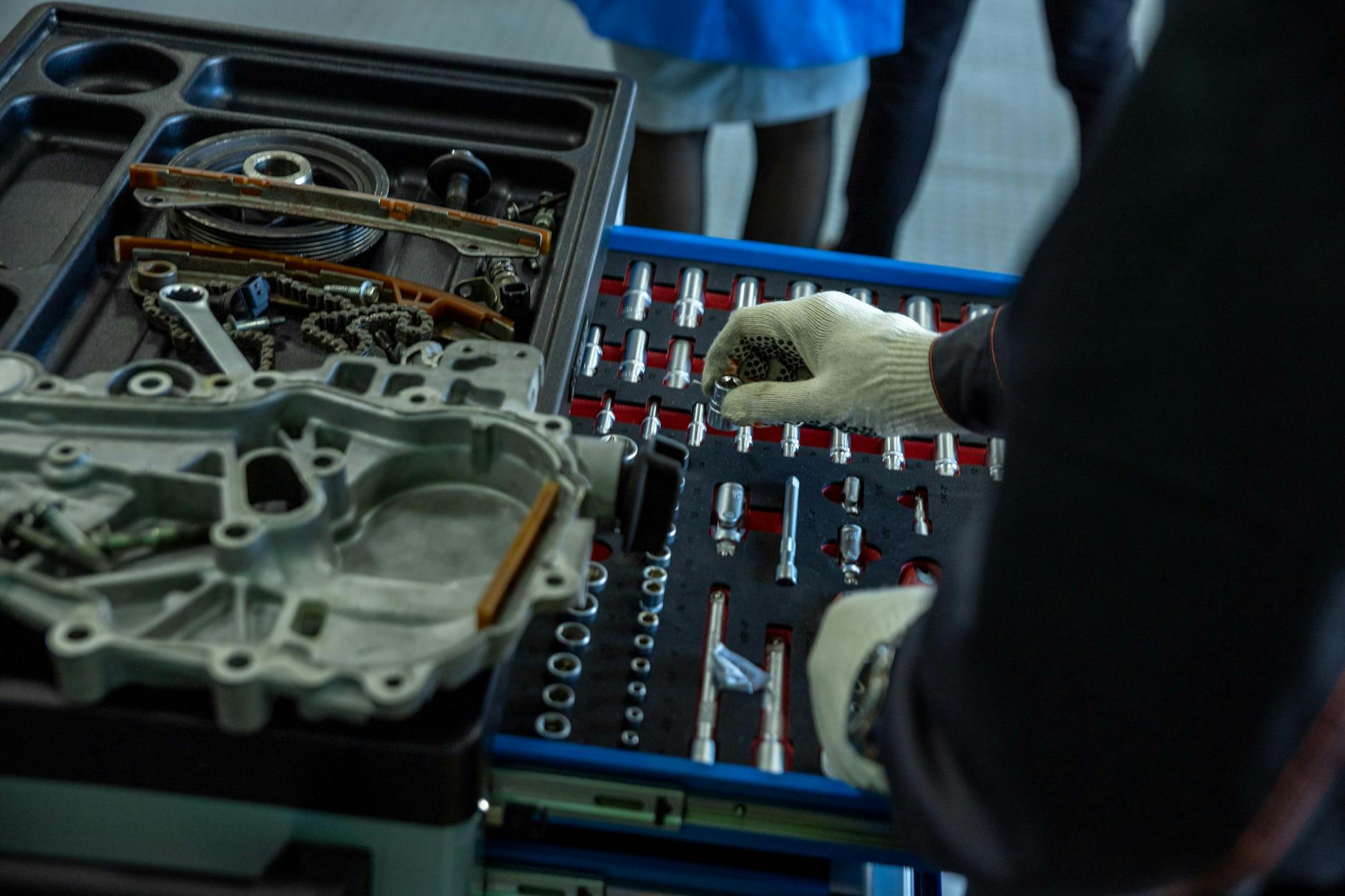 Mechanik w rękawicach porządkuje części i narzędzia w warsztacie Mercedesa