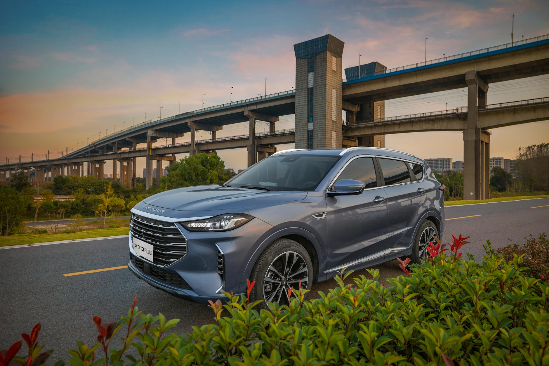 Niebieski SUV Ford na malowniczej drodze z mostem o zachodzie słońca