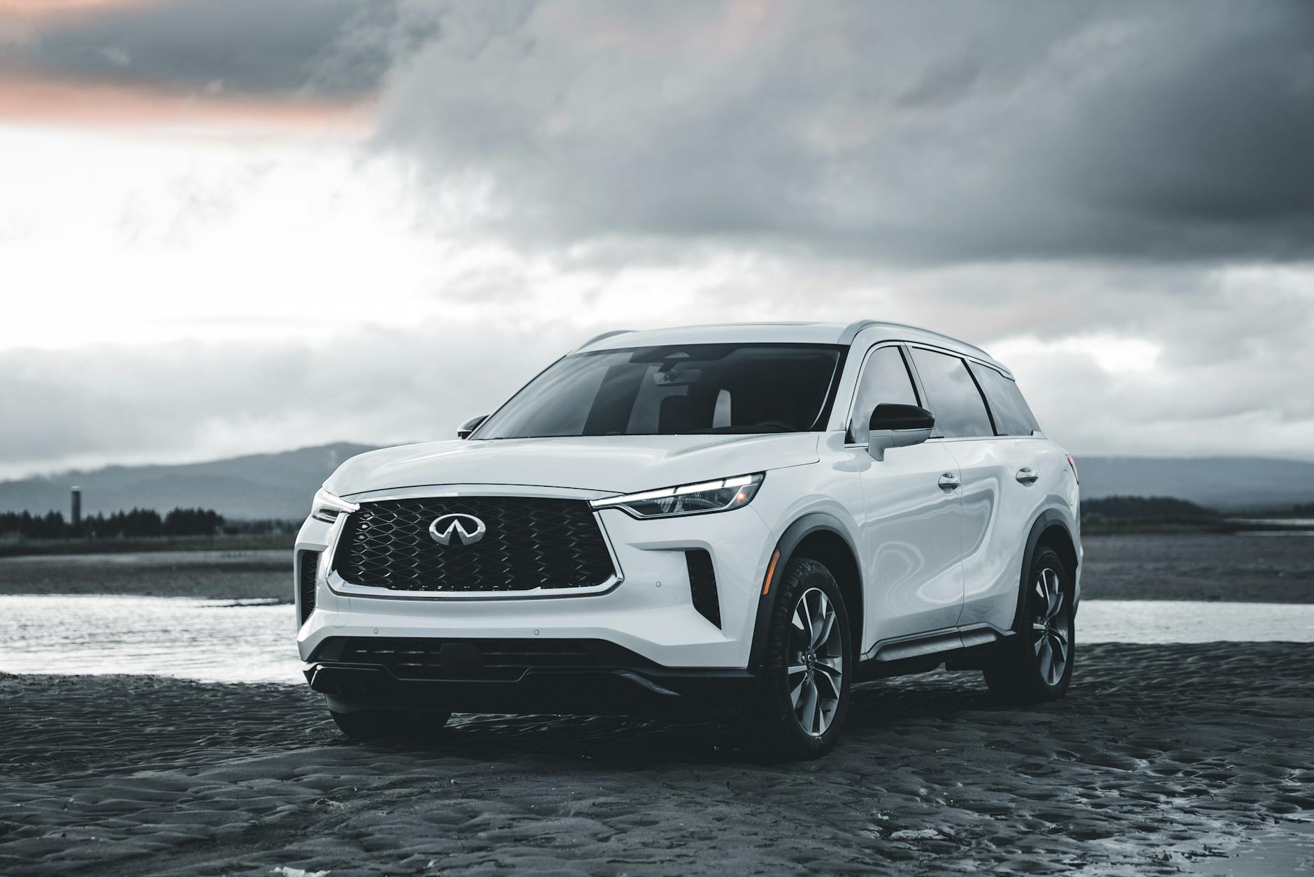 Biały luksusowy SUV Mercedes-Benz zaparkowany na plaży pod chmurami