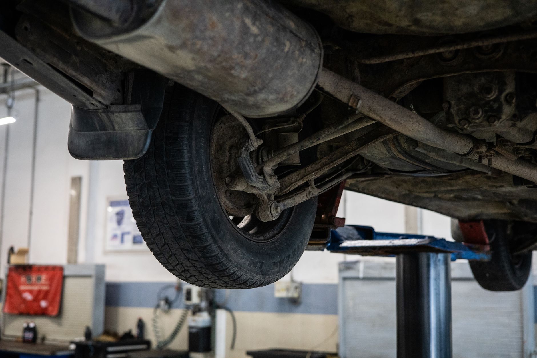 Jak sprawdzić i samodzielnie zdiagnozować niepokojące dźwięki zawieszenia w Suzuki Mechanik ogląda podwozie samochodu Suzuki na podnośniku w serwisie