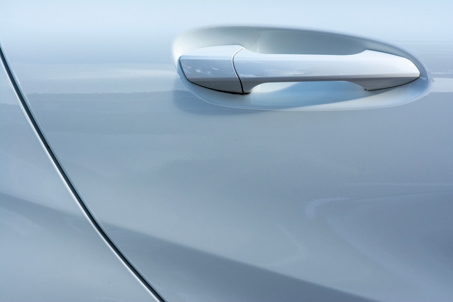 Jak działa system drzwi Rolls-Royce z domykaniem i osłoną przed deszczem w praktycznym użytkowaniu Zbliżenie na klamkę drzwi białego Rolls-Royce’a