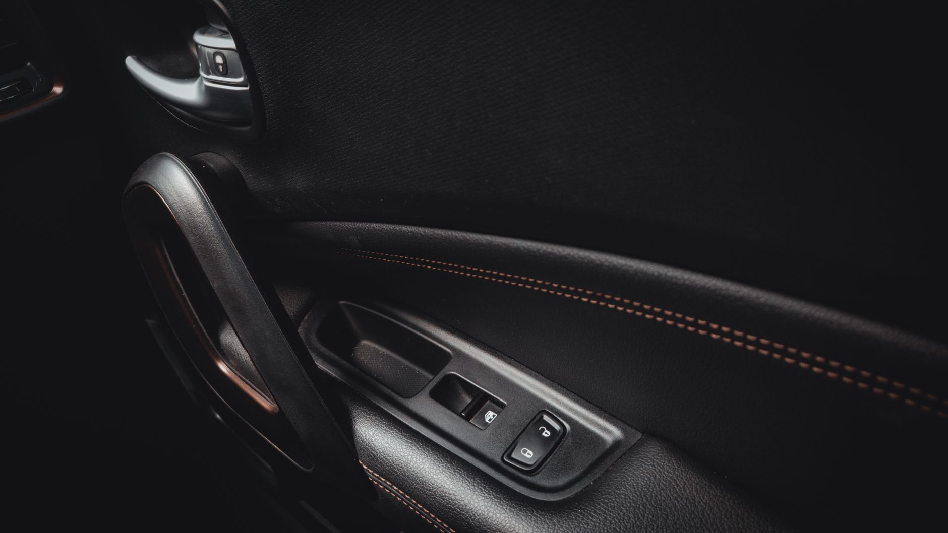 Zbliżenie wnętrza drzwi Rolls-Royce z klamką i przeszyciami skóry