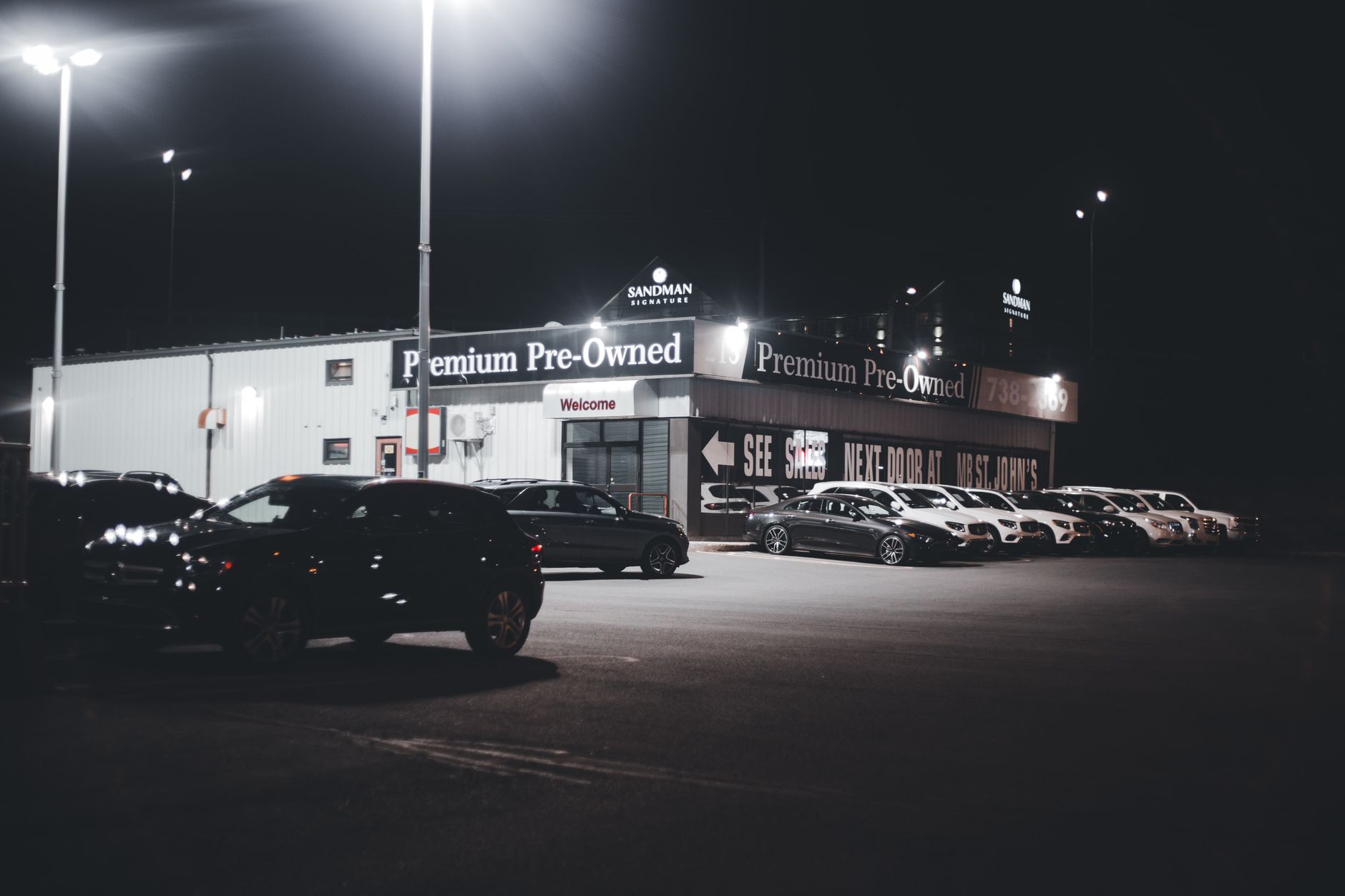Nocny plac komisu z oświetlonymi samochodami używanymi