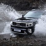 SUV Jeep brodzi w skalistym potoku, rozpryskując wodę w terenie