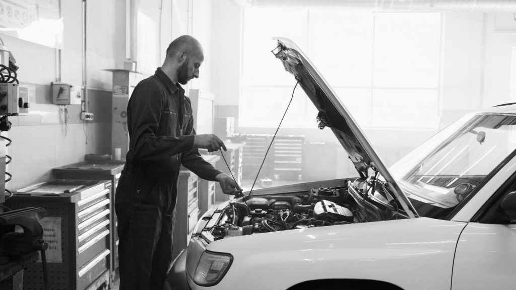 Mechanik sprawdzający silnik używanego Peugeota w warsztacie